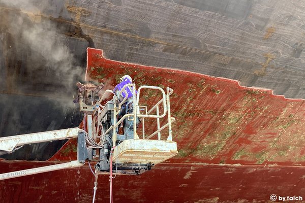 hull maintenance using a steam jet and work platform in the shipyard.